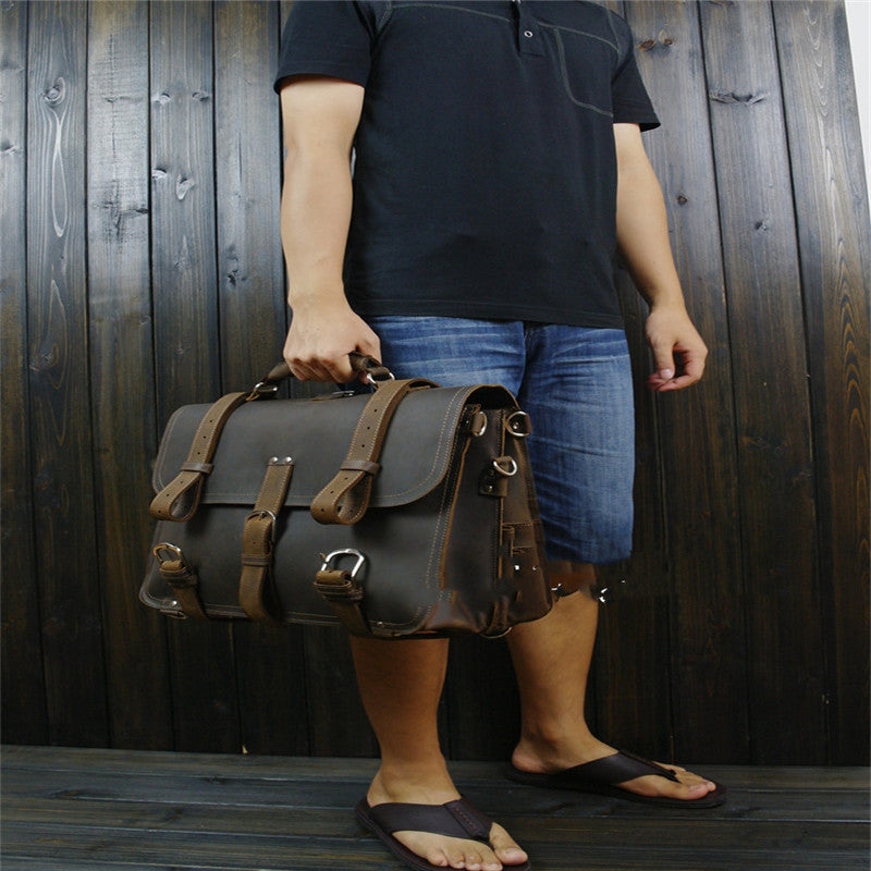 Person holding a leather satchel bag against a wooden background